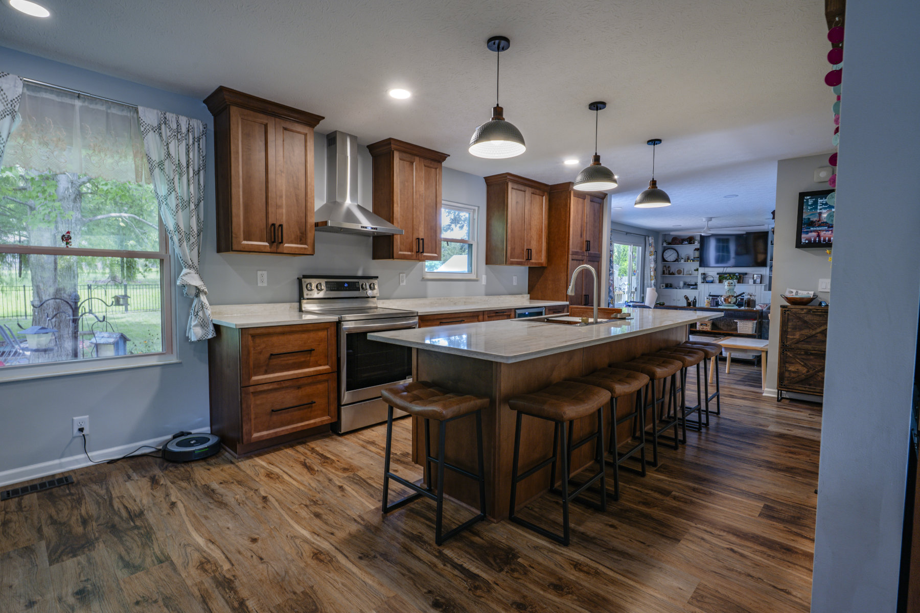 Remodeled kitchen with new wood cabinets island stools stove and range hood zoomed in